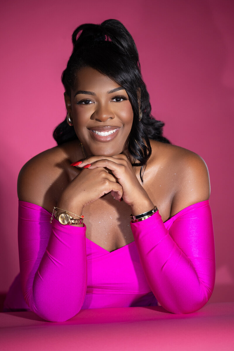 Corporate photo of woman in pink dress with pink backdrop
