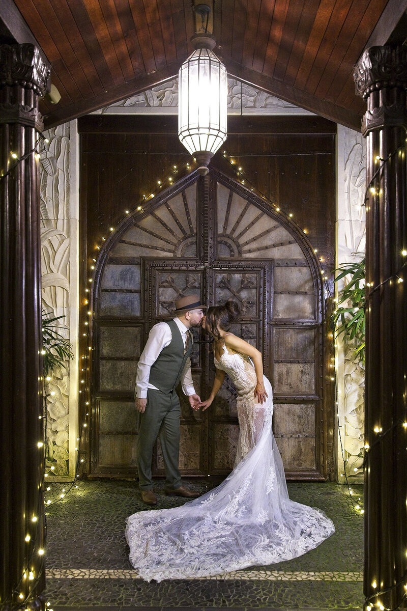 Wedding couple kissing at Villa Botanica in front of doorway.