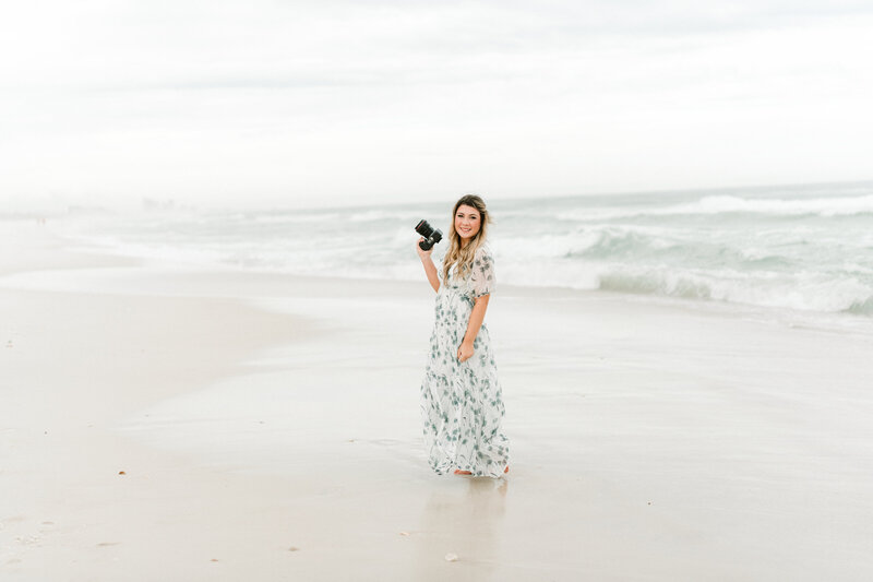 Abby Bell, a fine art wedding and portrait photographer in Alabama, captured on a beach with her camera. Specializing in luxury and personalized photography, Abby Bell Photography provides romantic wedding, engagement, and couples sessions, delivering timeless and fine art portraits across Alabama.