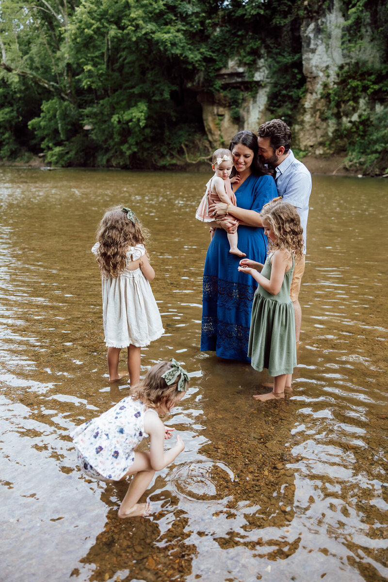 Family of six standing in a creek playing and cuddling during a lifestyle portrait session in Farmington, Missouri. 