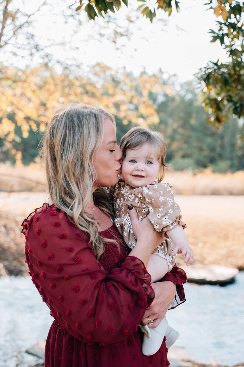 Mom kisses baby girl on cheek.