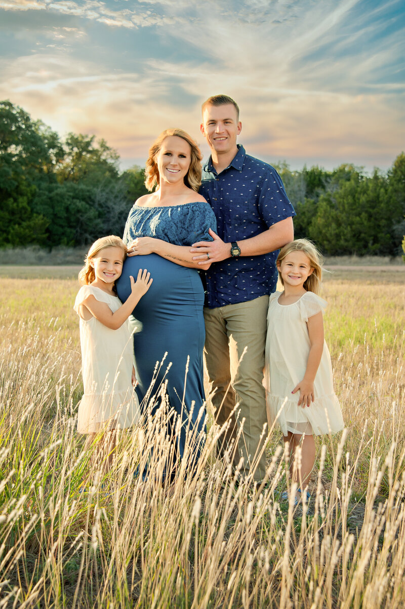 Family of 4 in a field during a family maternity session near Clermont, FL taken by Melissa Vinsik Photography
