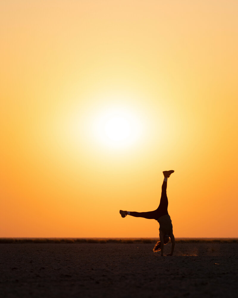 Astrotourism expert Stephanie Vermillion doing a cartwheel with a bright orange midnight sun in background