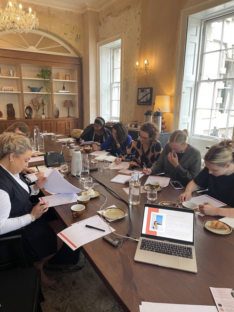 workshop attendees at a desk working and writing to papers