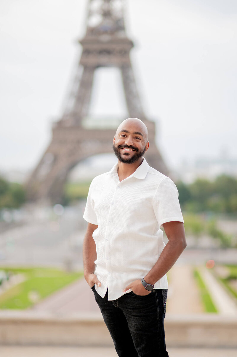 Award winning Dallas Fort Worth Photographer and Videographer Mente Bezuneh, standing in front of the Eiffel tower in Paris, France