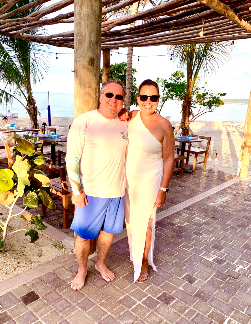 Man and woman wearing white standing under wood pavilion on tropical Jamaica beach