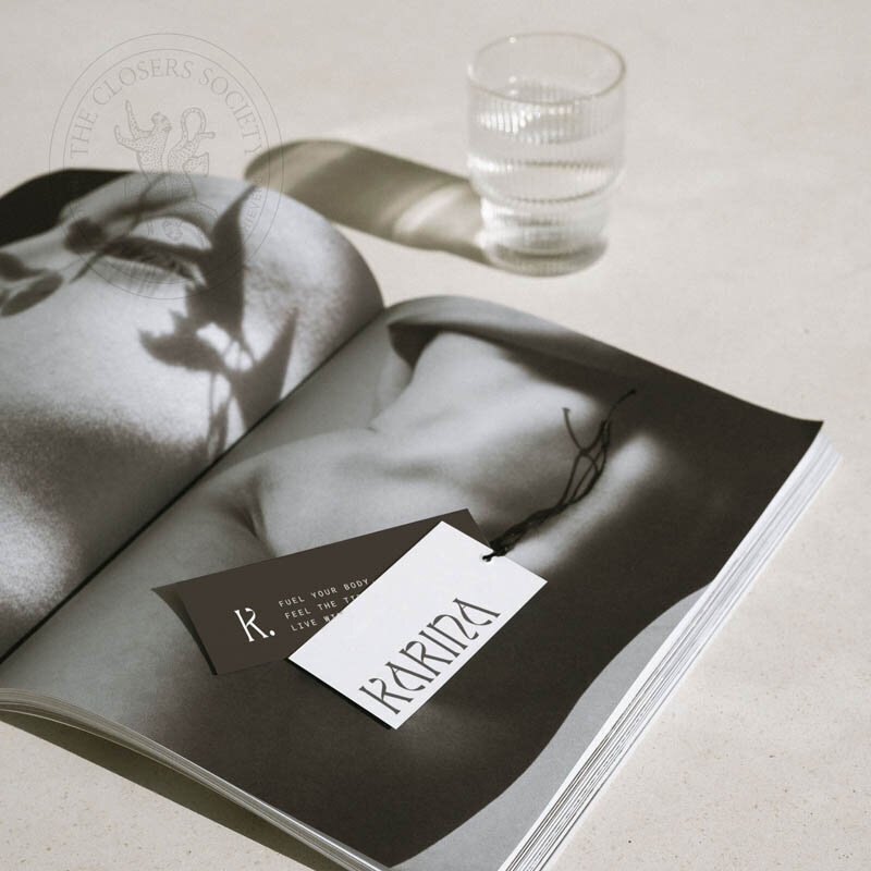 Karina Canva pre-made brand kit for wellness coaches featuring minimalist business cards on a neutral-toned magazine layout with soft natural lighting.