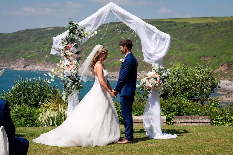 A bride and groom standing in front of a wedding arch