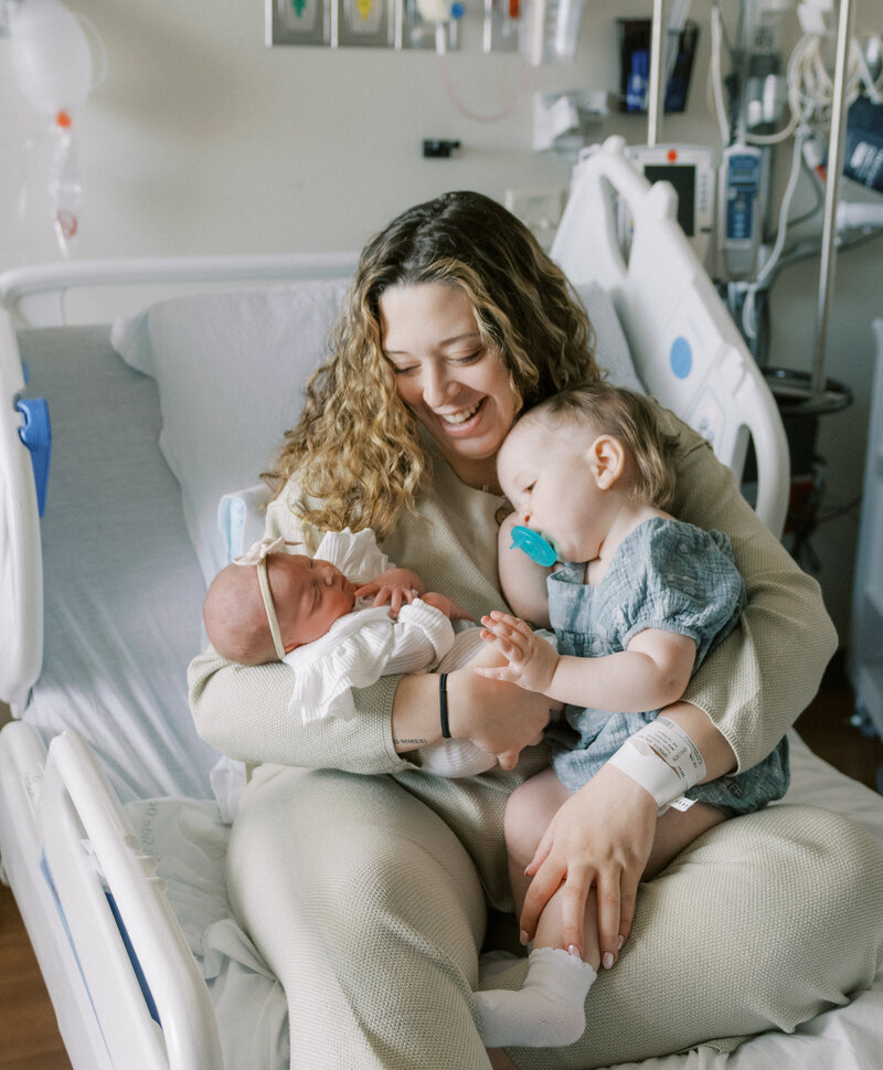 mom with newborn and sibling on hospital bed
