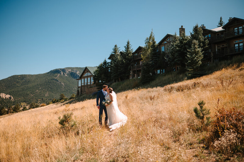 Bride and groom kissing through the grass field