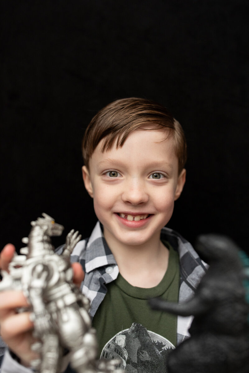 Elementary school boy wearing a checkered black shirt and showing a  close up of his favorite toy