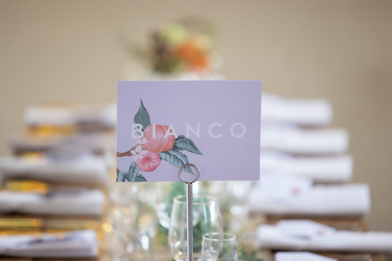 A card showing the table name 'Bianco' at an Italian wedding with a peach theme.