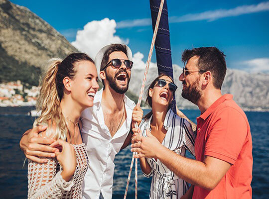 Segelyacht von oben auf dem Meer in tükisblauen Wasser und vier Menschen auf Luftmatratzen im Wasser