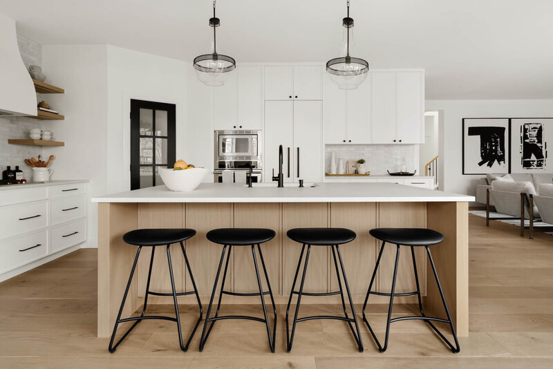 A modern farmhouse kitchen with plaster hoodfan, white oak open shelving and black accents paired with subway tile. 