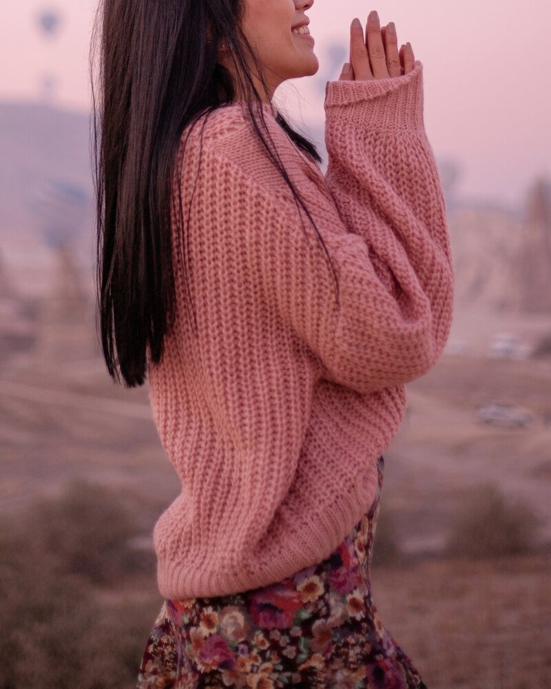 Side view of a woman with folded hands, reflecting on perimenopause coaching and mindfulness.