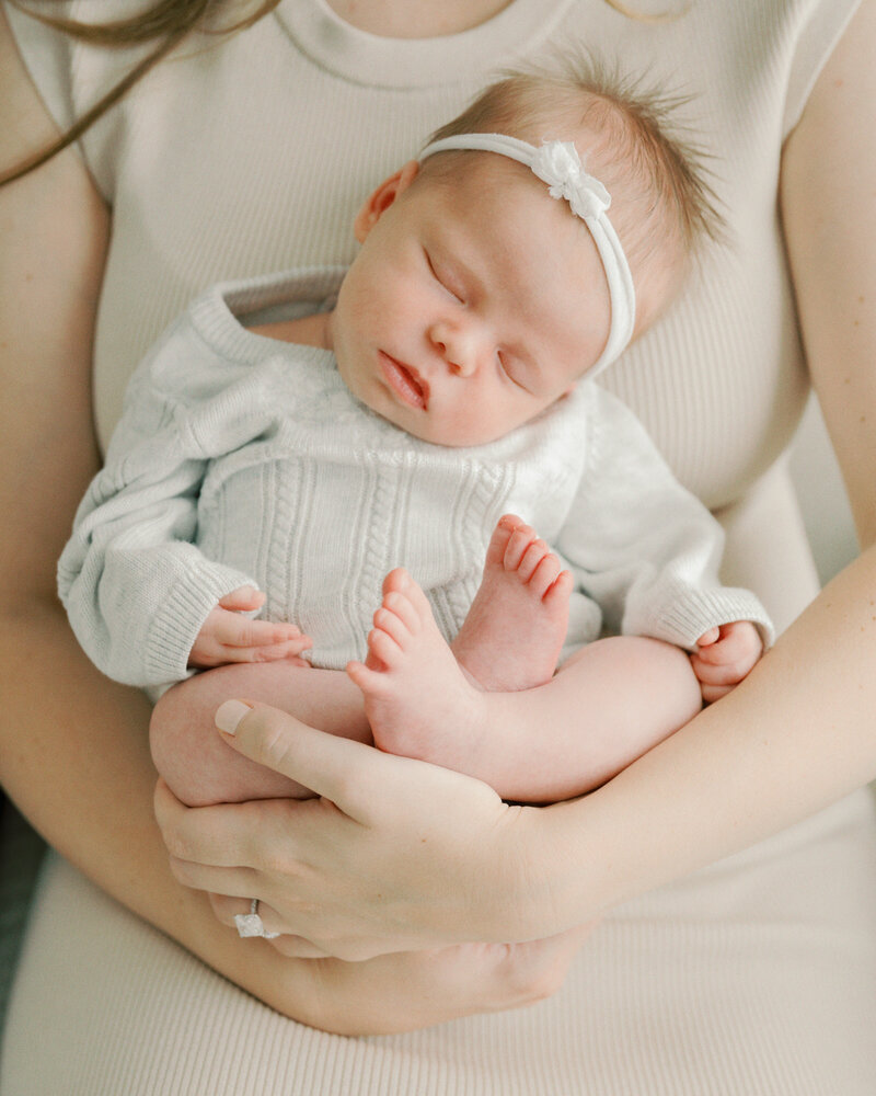 newborn being cradled by mother in chair