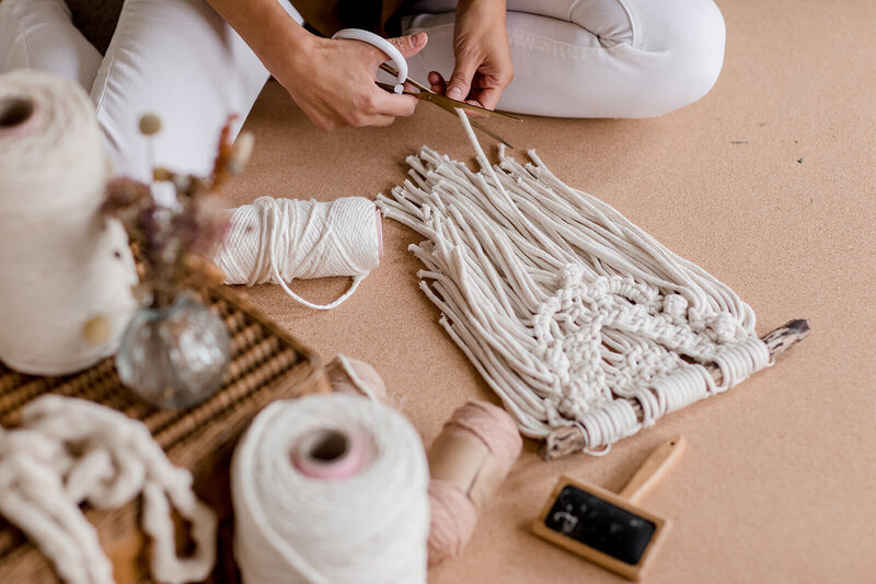 Isabella Strambio working on a  small macrame wall hanging in her studio