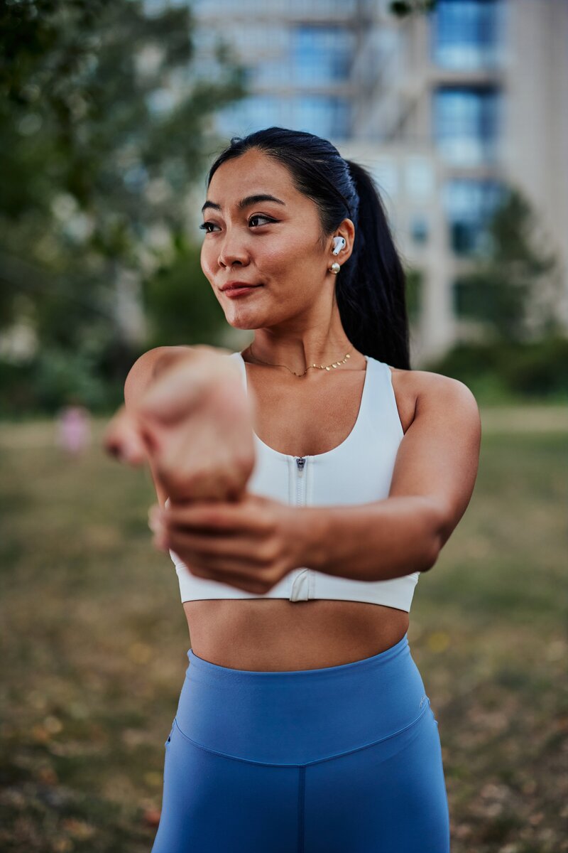 beautiful-sportswoman-stretching-her-arms-at-green-2024-10-16-10-01-18-utc