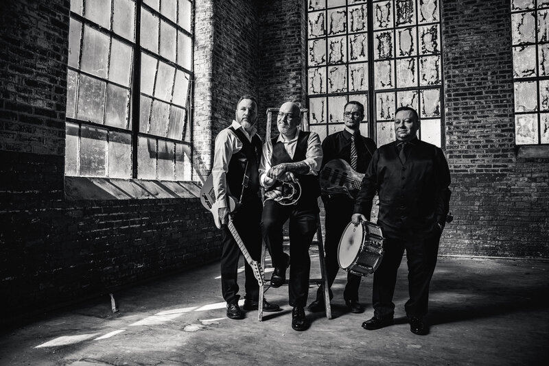 Black and white photo of a band standing in a rundown building 