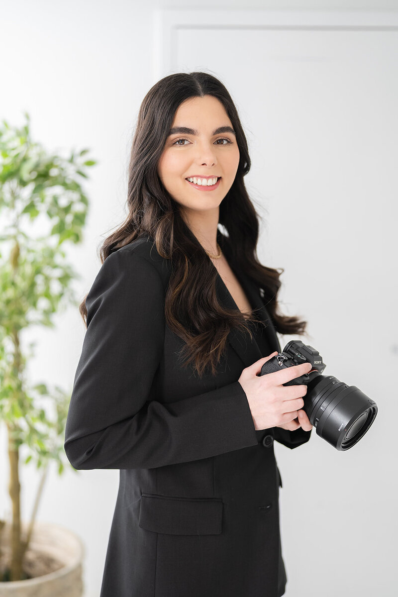 woman smiling while standing and holding a camera