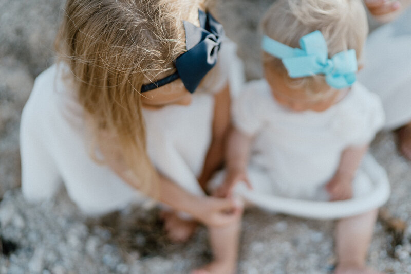 young sisters looking at shells on beach