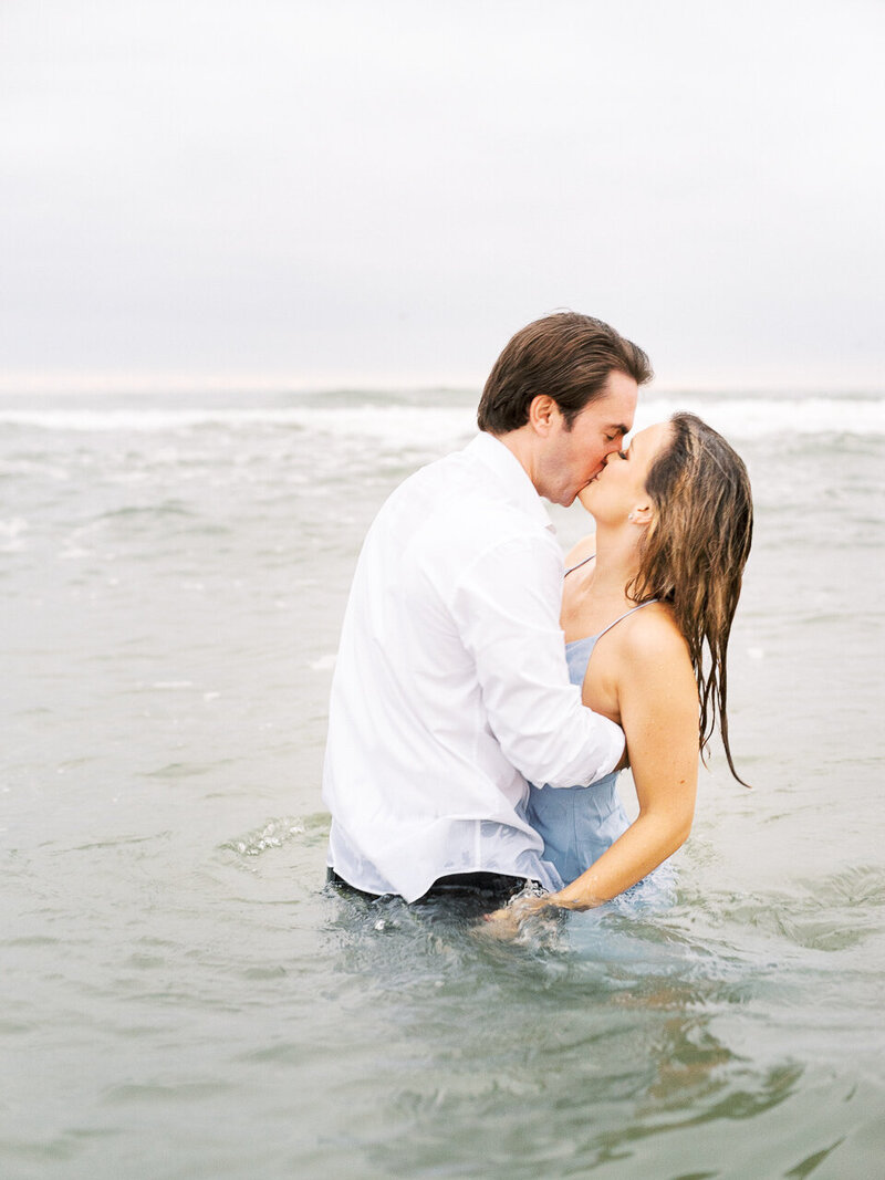Candid, natural engagement photography for the couple as he picks her up and spins her around in the ocean close to the beach nearby in California.