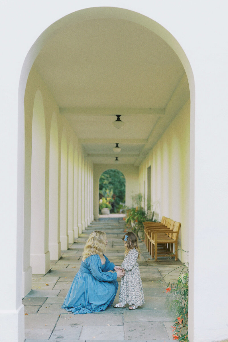 mom kneeling down to daughter and holding hands