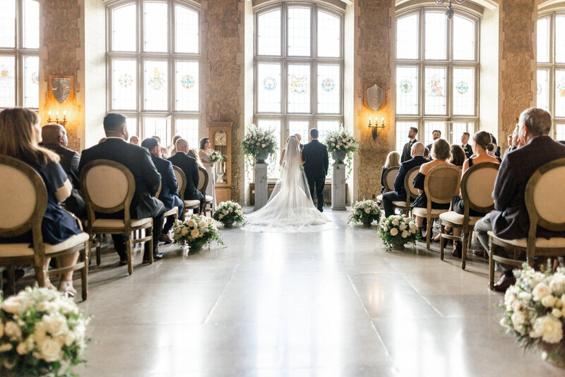 Capture the love and emotion of a wedding ceremony inside Banff Springs Hotel's Mount Stephen Hall. A beautiful photo of the bride and groom exchanging vows with guests seated and enjoying the moment.