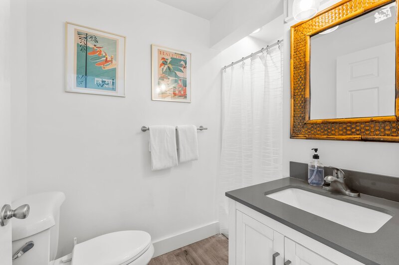 Clean, modern bathroom with bamboo mirror and coastal artwork, part of the 3-bath Tropical House rental in Panama City Beach.
