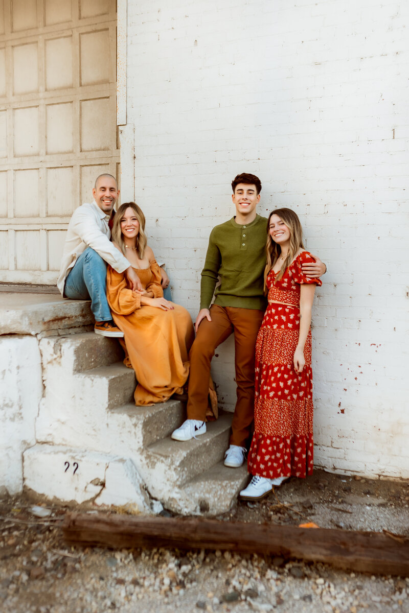 Mom and Dad sit on stairs with their two children at urban Kansas City session with Maternity Photographers.
