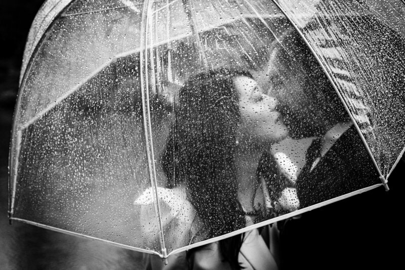A couple kiss under their umbrella on a rainy NYC wedding day