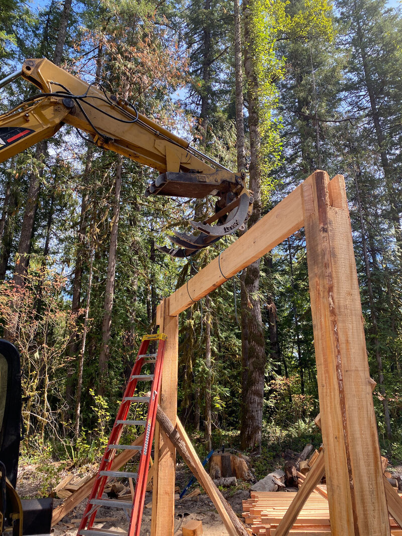 Machinery lifting wood onto a tall wooden frame under construction