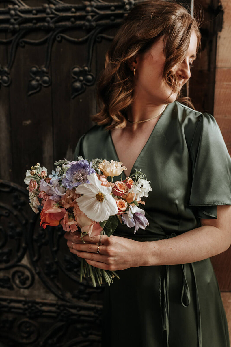 Bridesmaid holding a bouquet of flowers wearing a green satin dress