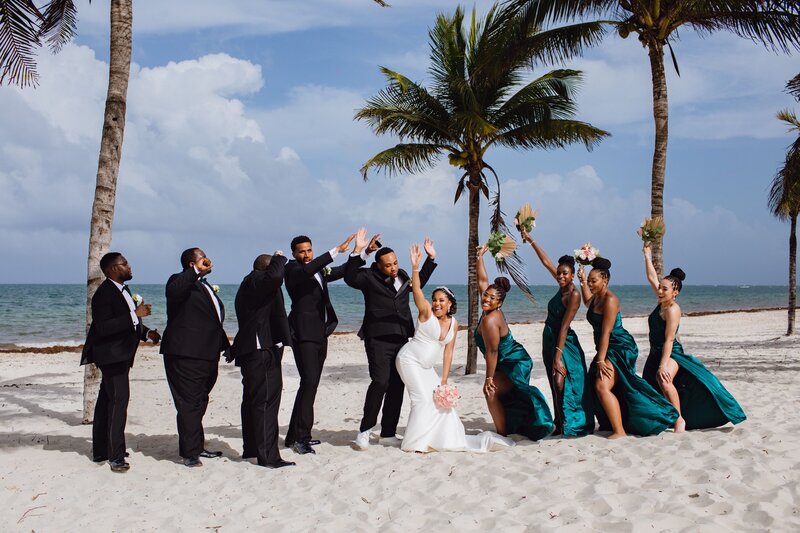 A wedding party on the beach with palm trees in the background.