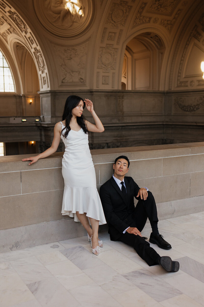 A couple poses at SF City hall leaning against wall