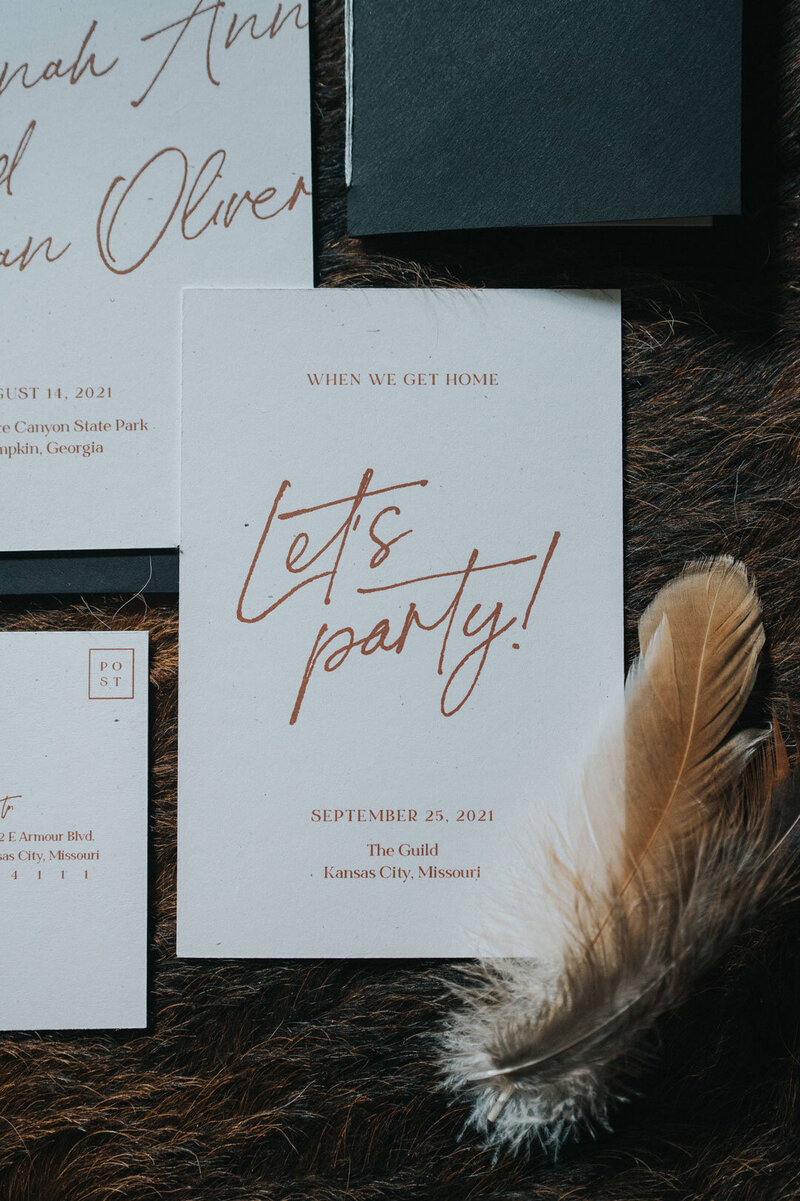 White wedding invitations with orange script font that says "let's party!"