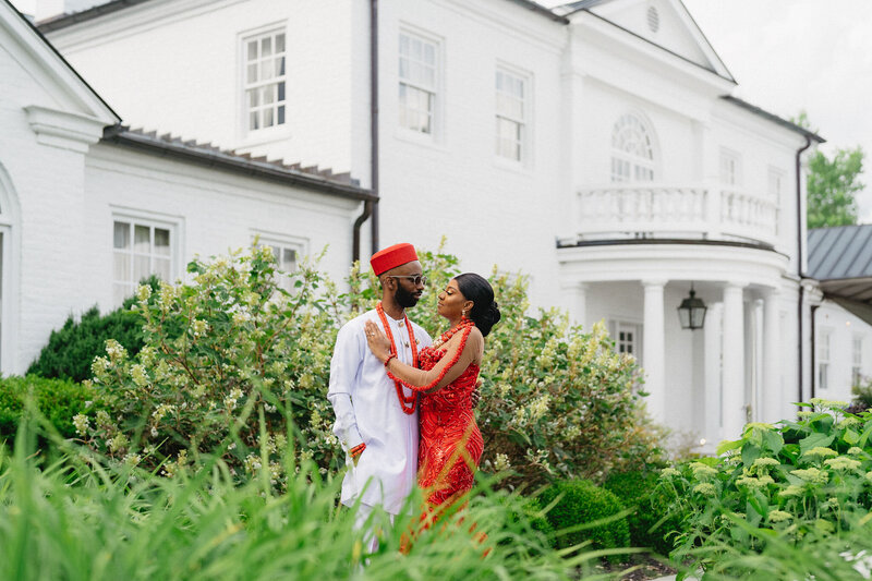 Ob & Alix pose in their traditional haitian wedding outfits in front of court manor white house in virginia