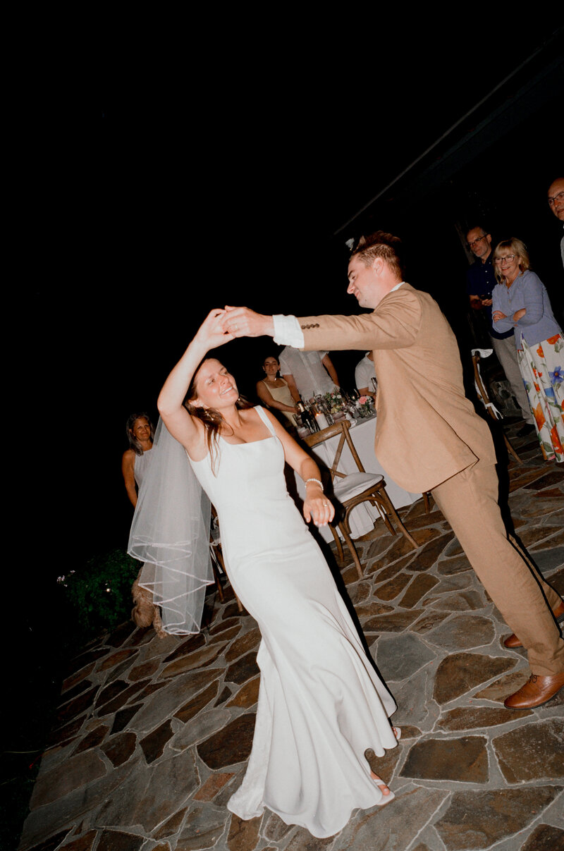Film photo of a bride and groom sharing a joyful first dance under the night sky during their micro wedding in Connecticut — a lively candid made by a film wedding photographer.
