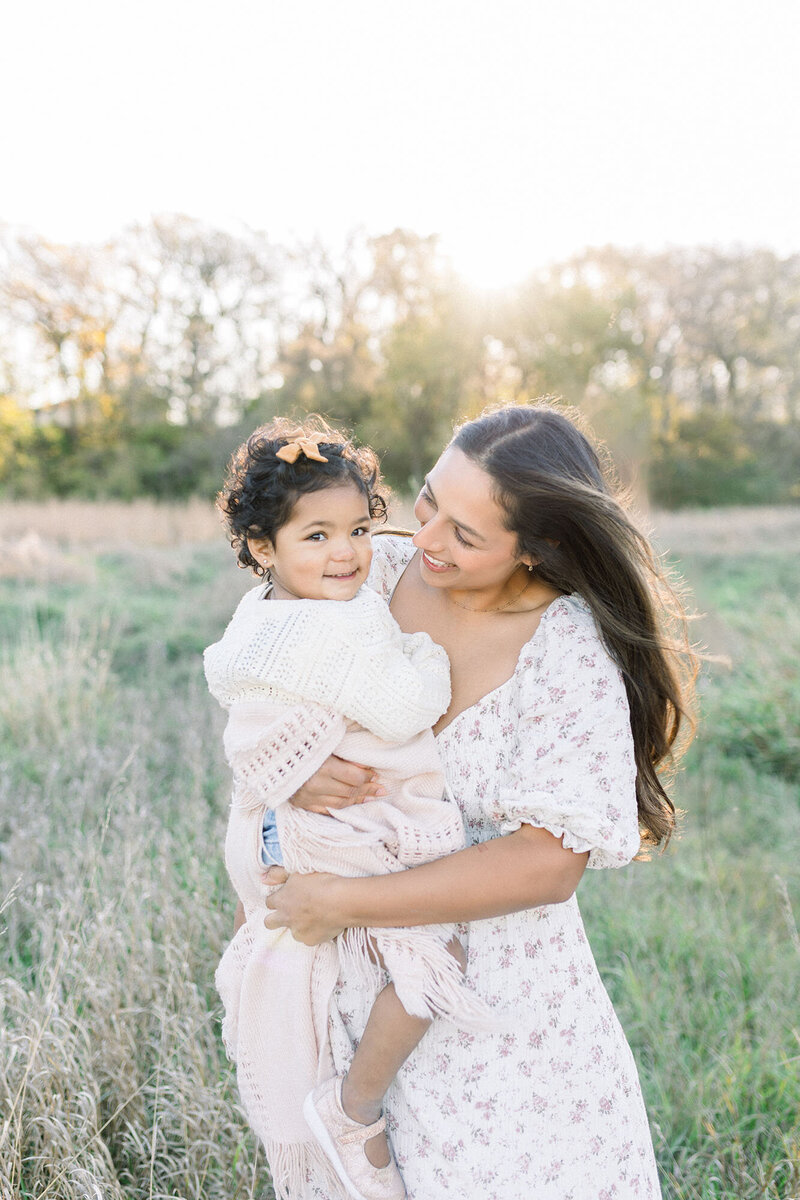 A mom holding her toddler daughter during their sunrise session at turtle river state park with grand forks photographer chelsea nichole photography. 