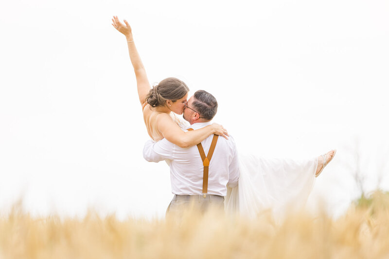 Grey Loft Studio - Bethany and Luc Barette - Wedding Photography Wedding Videography Ottawa - Boho Couple Groom Wearing Suspenders Lifting Bride in Field