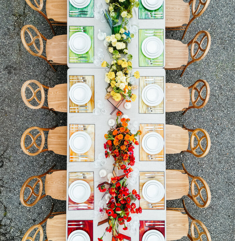 Colorful wedding reception tablescape with red, yellow, and green floral centerpieces and modern place settings