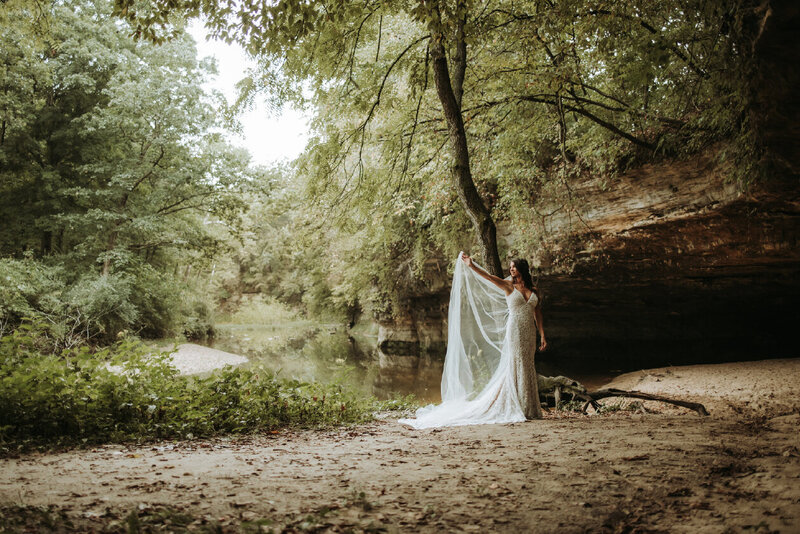 bride-holding-veil-in-forest
