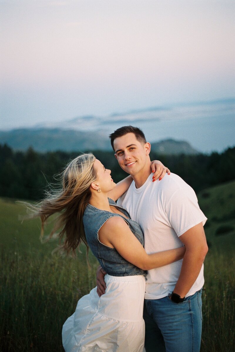 man and woman embracing with hills in the background