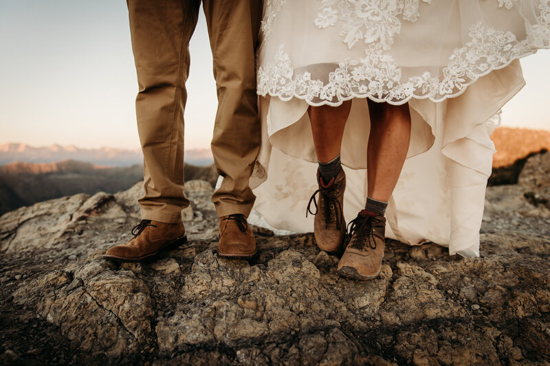 Couple in boots standing on mountain top during elopement
