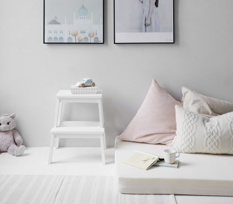 Bright white room with picture frames and soft textiles and kids tous