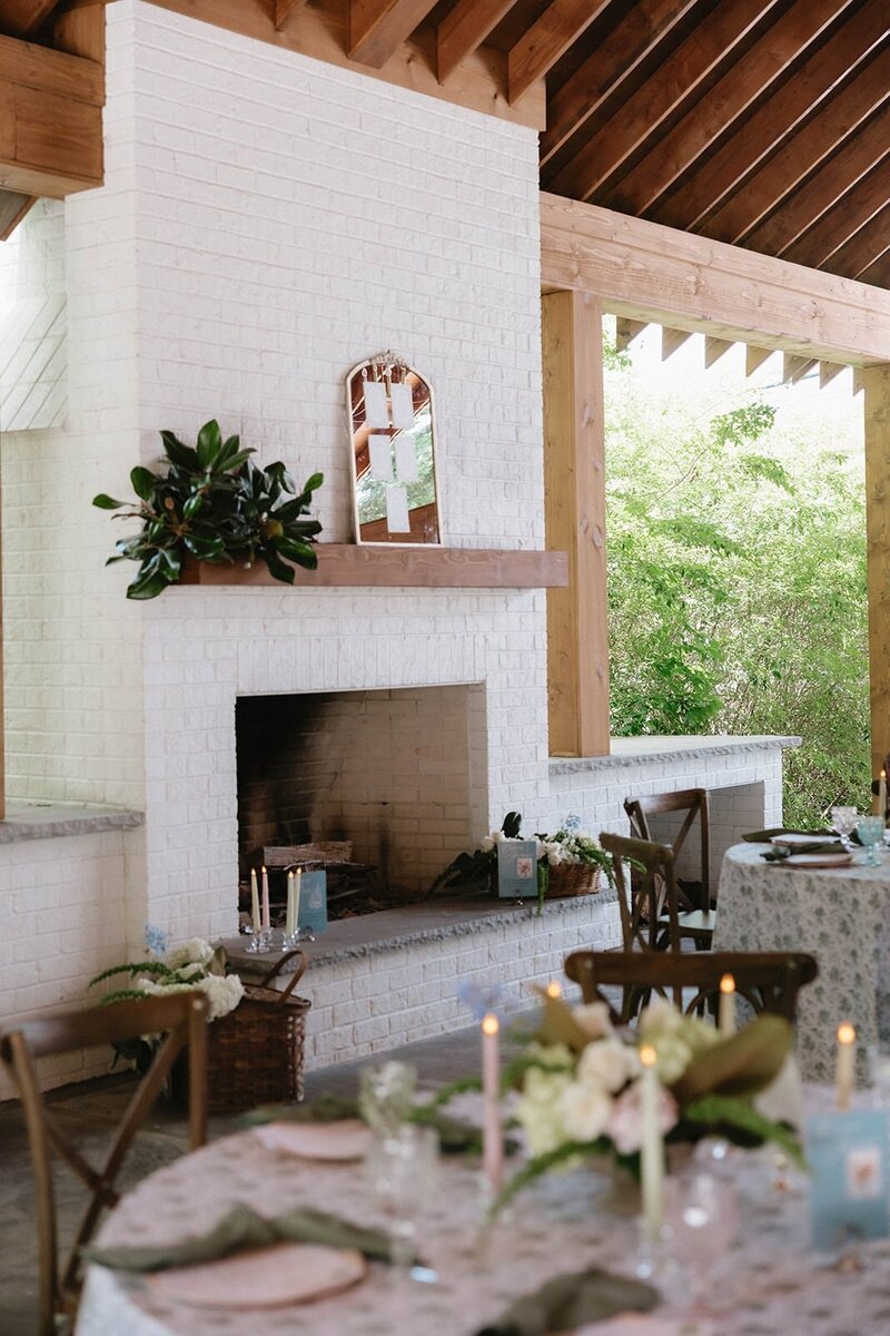 A sophisticated wedding reception table adorned with white candles and delicate florals in soft yellow hues, creating a warm and intimate atmosphere for the celebration.