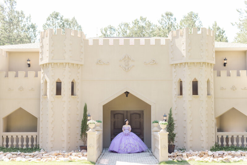 woman in large purple dress standing in large stone doorway