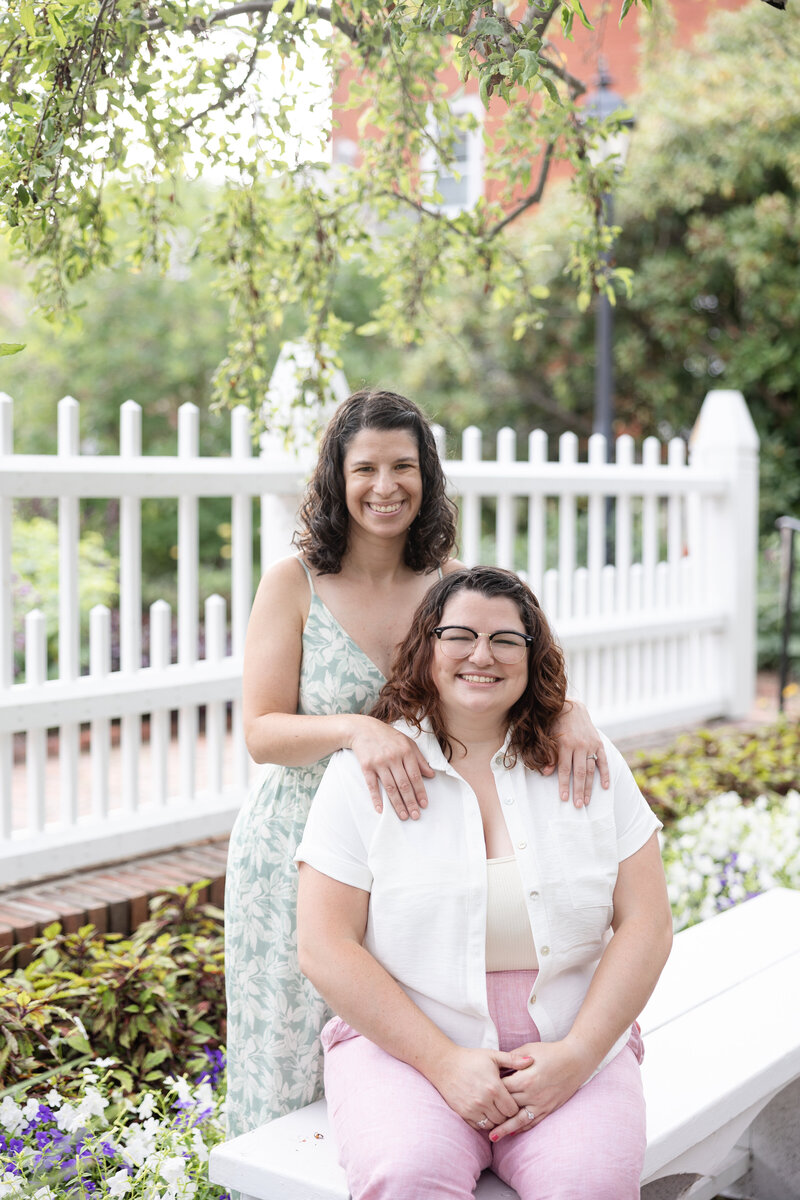 Engaged lesbian couple embracing in a colorful garden, captured during their New England engagement session.