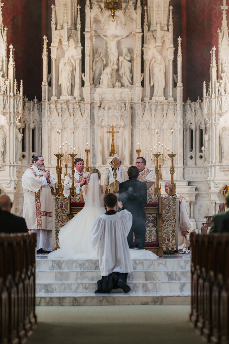 Eucharist raised above kneeling couple during the wedding Mass at Holy Family Cathedral