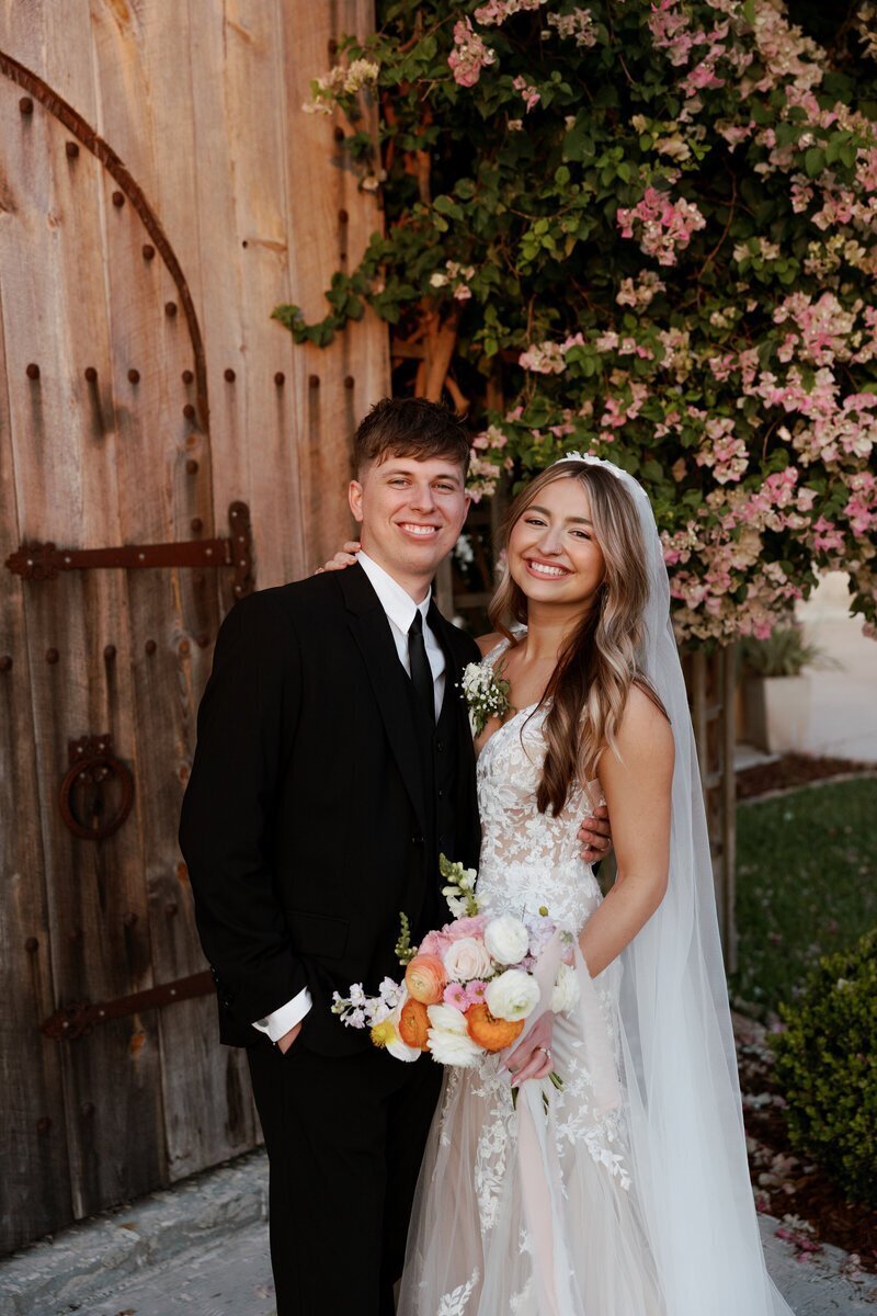 Bride and groom smiling in front of wedding venue by film wedding photographers Noble Photo Co